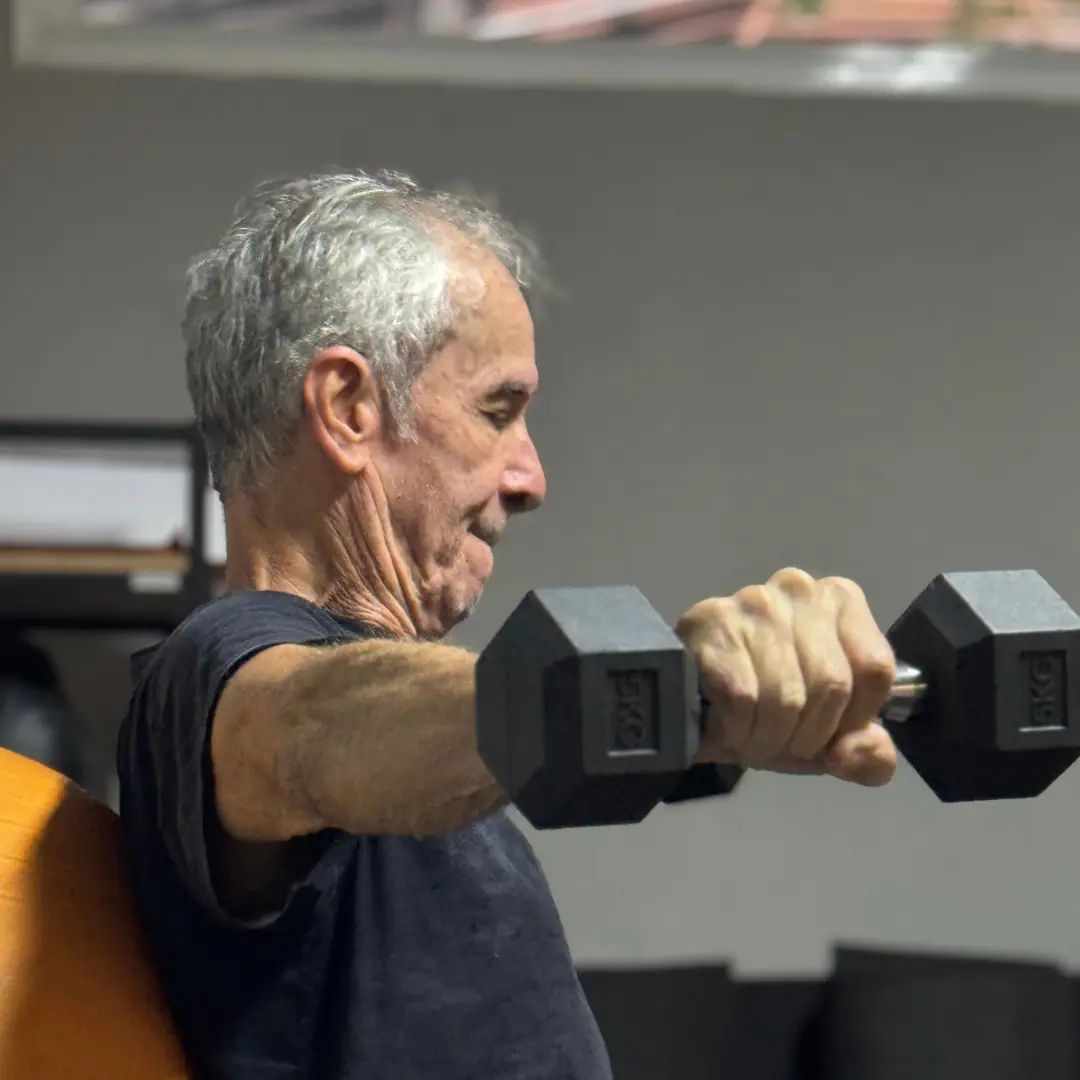 Aluno executando exercício de força com halteres no studio
